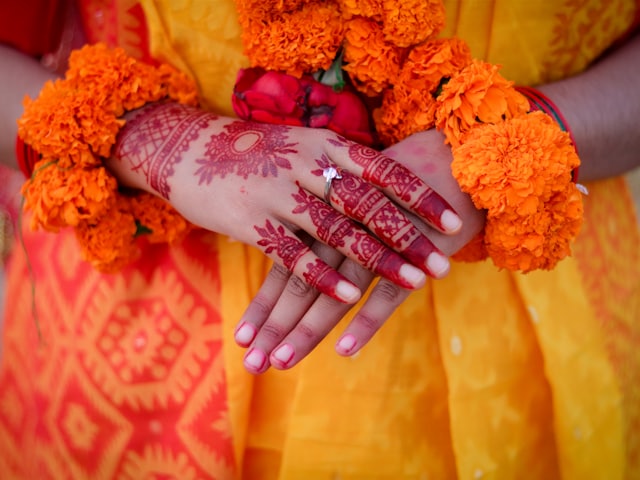 Hands adorned with mehendi and marigold garlands
