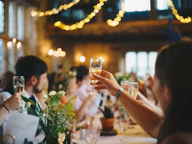 Wedding guests raising champagne glasses down a long candlelit table