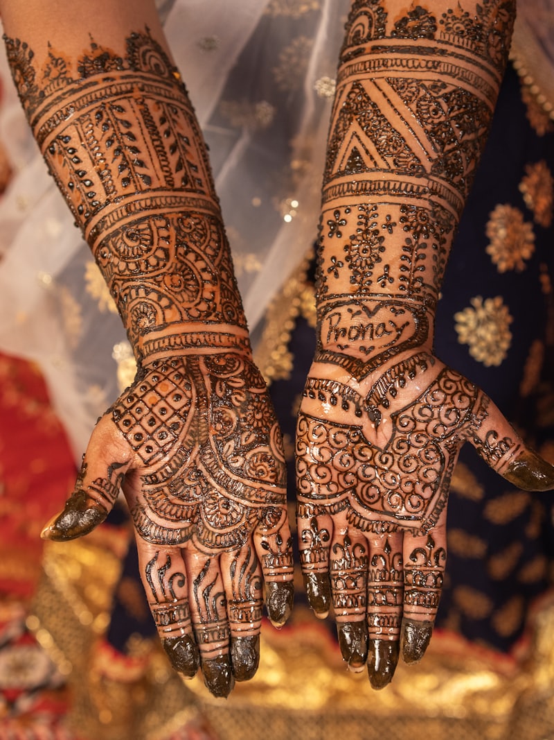 A bride’s forearms covered in intricate mehendi, resting over an embroidered red textile